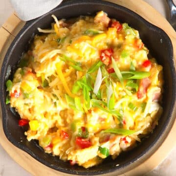 Grandma's scrambled eggs with cheese and veggies in cast iron pan.