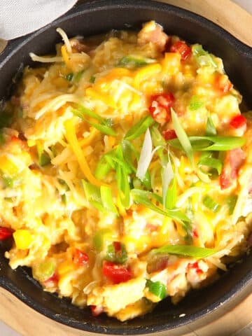 Grandma's scrambled eggs with cheese and veggies in cast iron pan.
