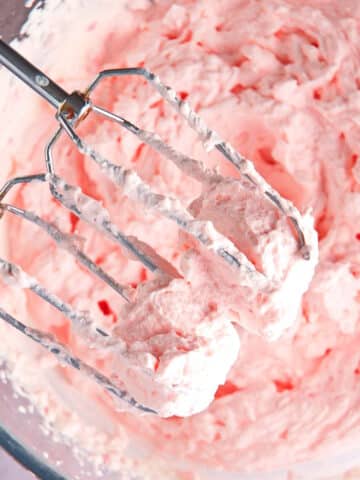 Grenadine whipped cream in bowl with electric mixer.