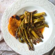 Grilled asparagus and orange slices on white plate.