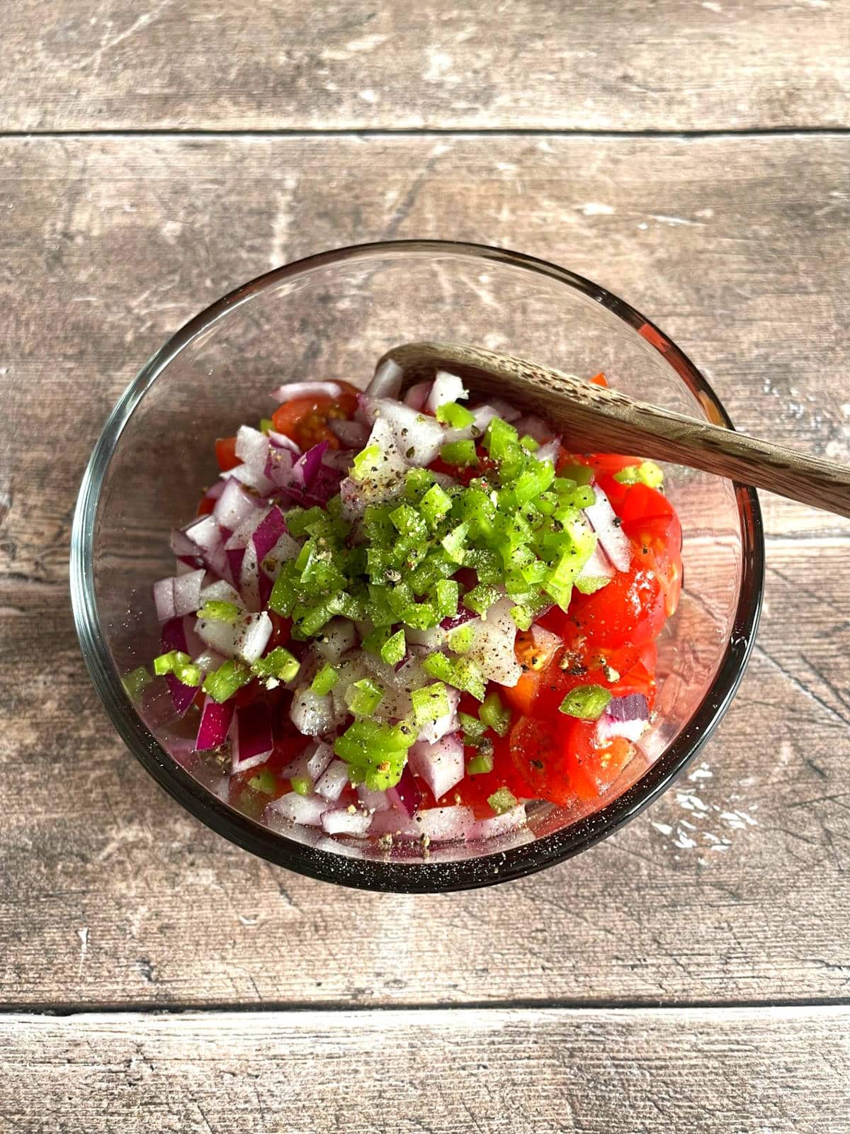 Pico de gallo ingredients in small bowl with spoon.