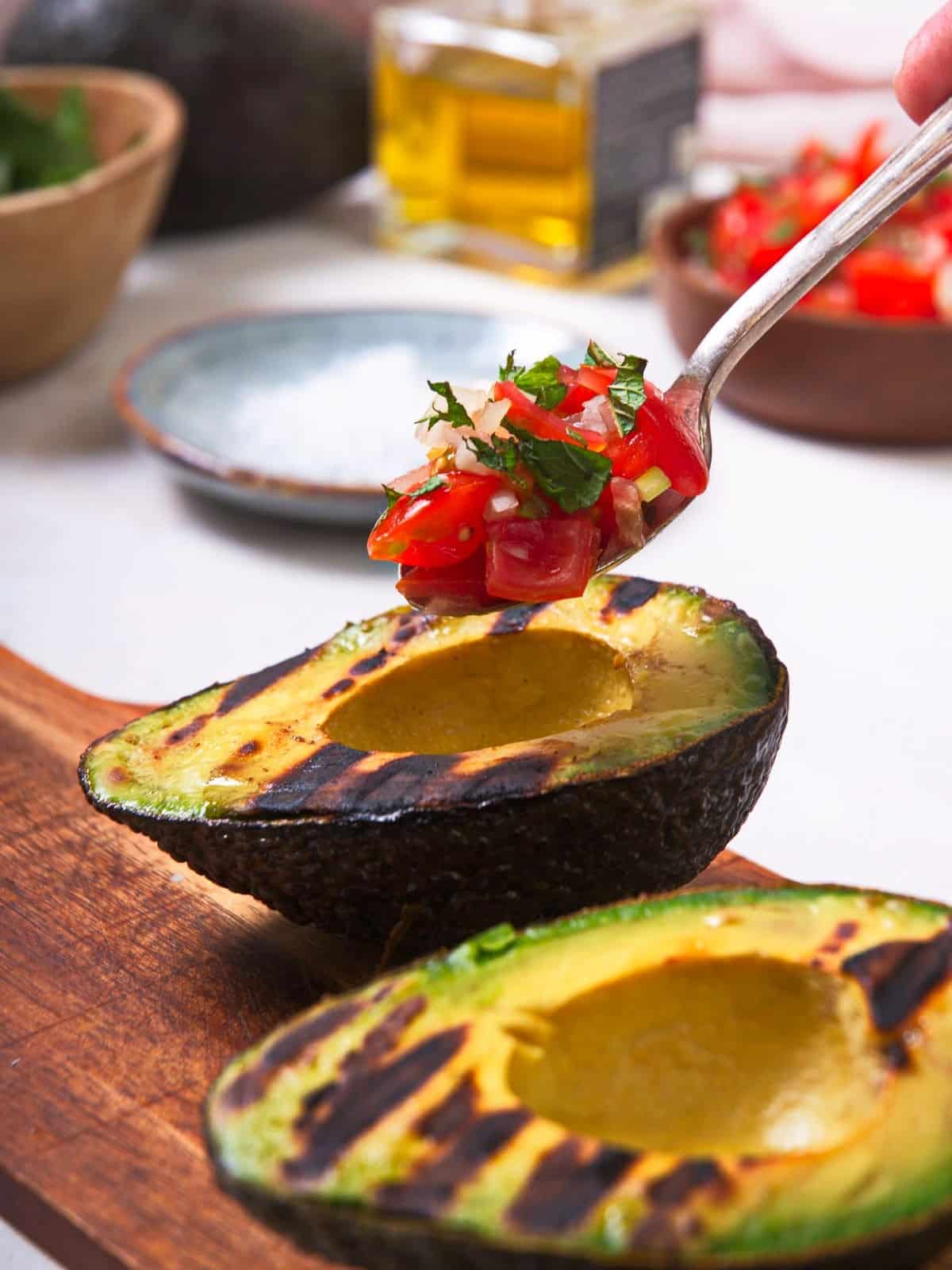 Grilled avocados getting stuffed with pico de gallo.