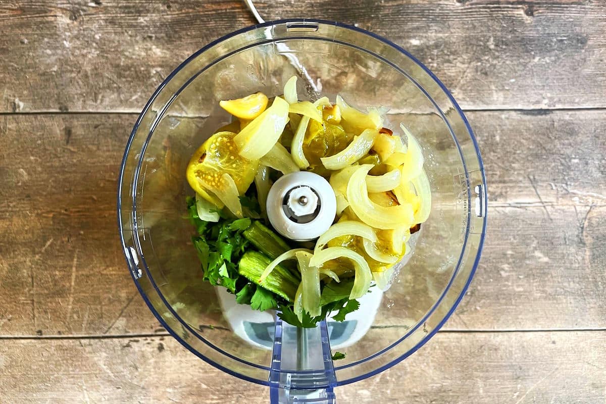 Cooked tomatillo salsa ingredients in food processor.
