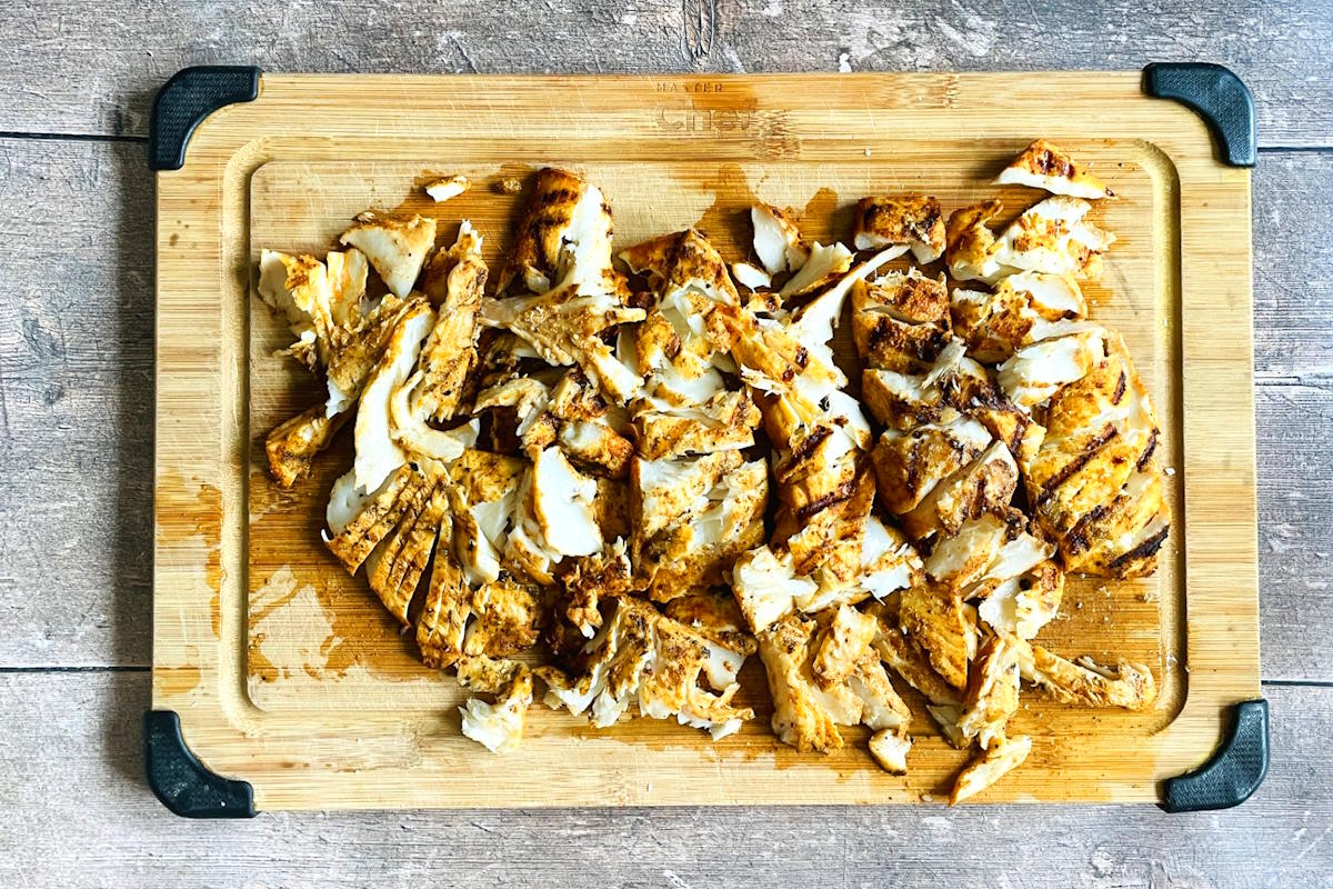 Grilled halibut flaked on a cutting board.