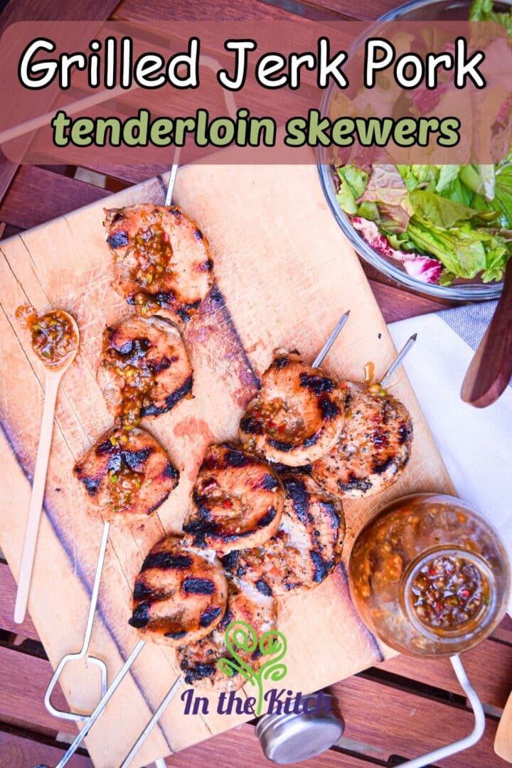 Grilled pork skewers on serving board with text overlay that says 'grilled jerk pork tenderloin skewers'.