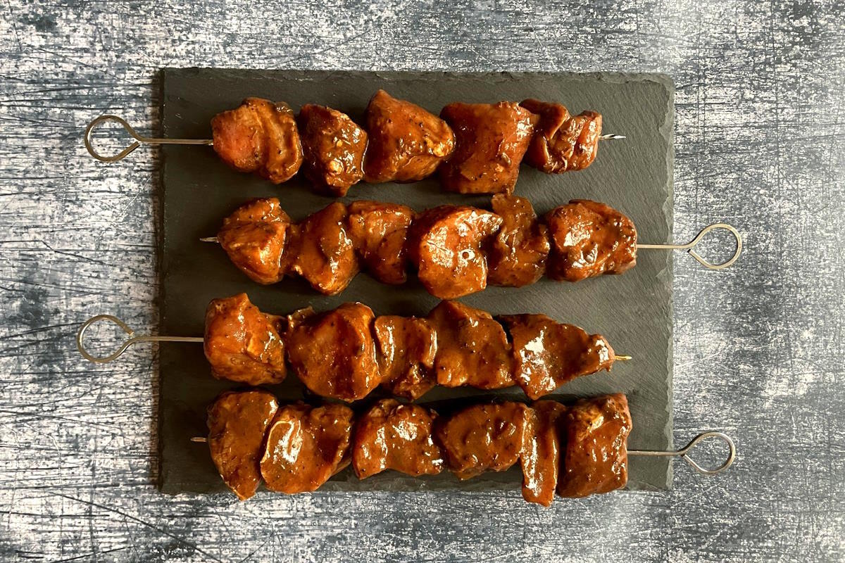 Raw pork cubes on metal skewers.