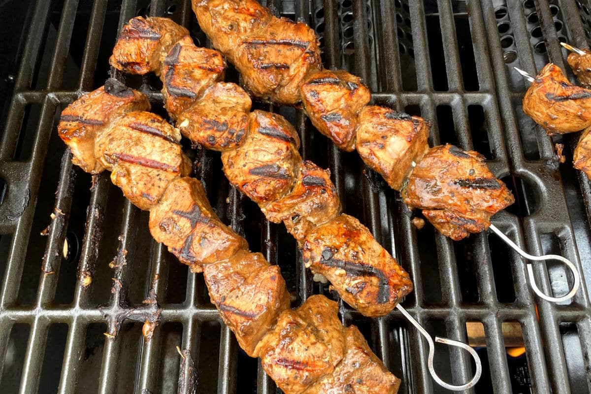 Jerk pork tenderloin skewers cooking on the grill.