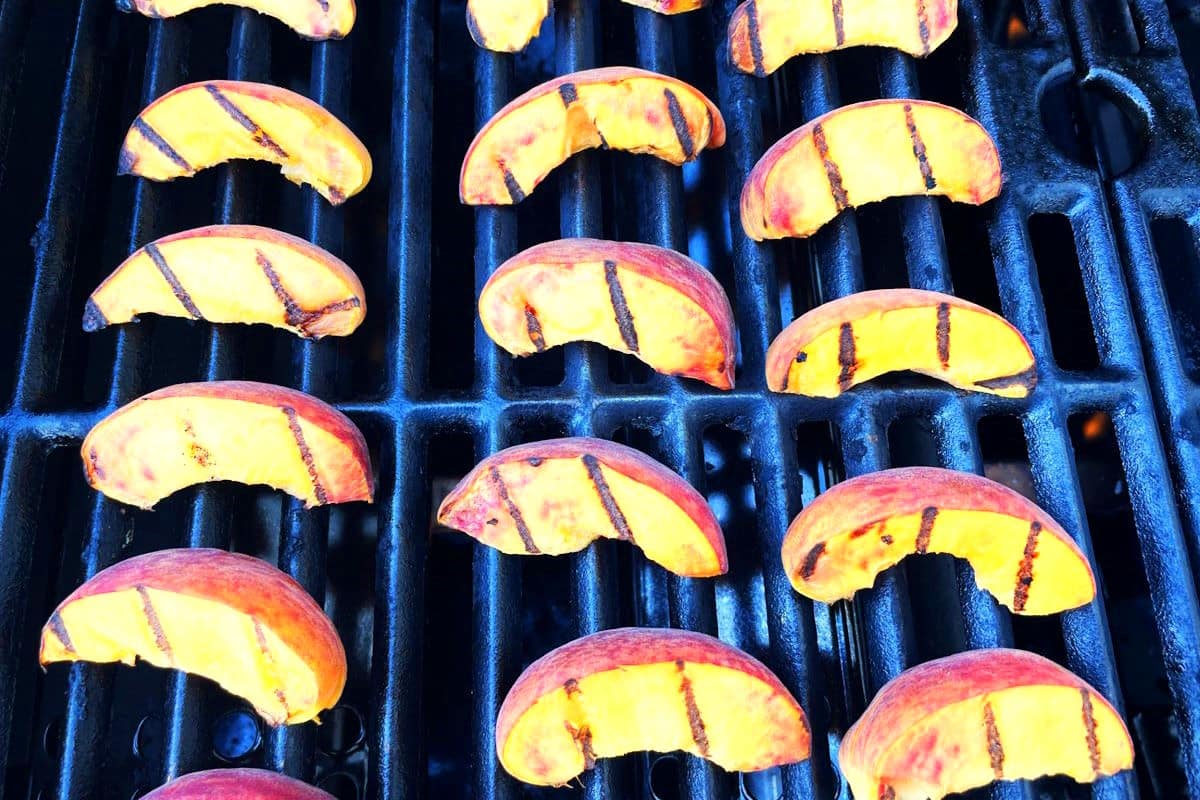 Grilled peach wedges on outdoor grill.