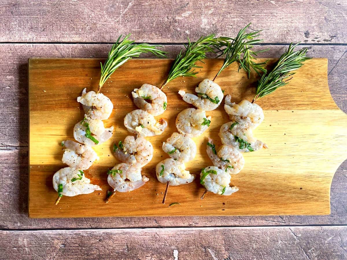 Raw shrimp on rosemary skewers.