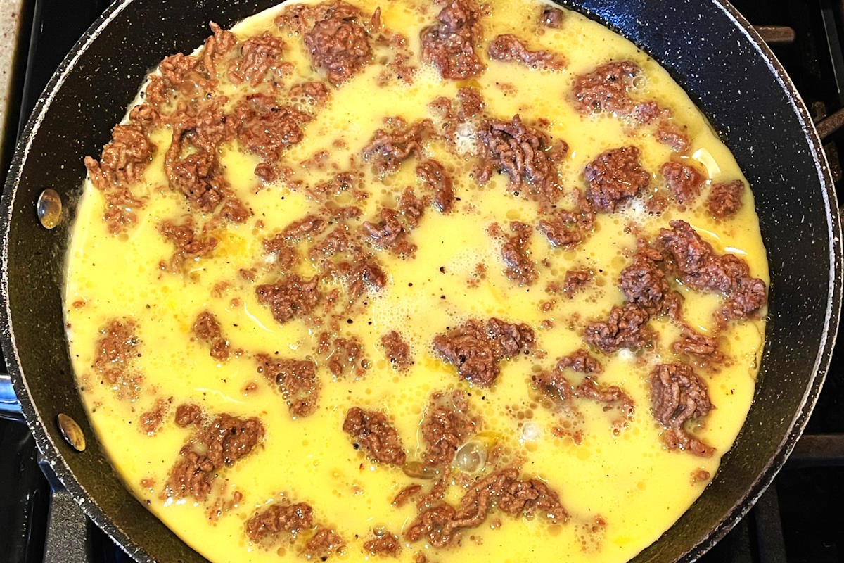 Ground beef and eggs in pan.
