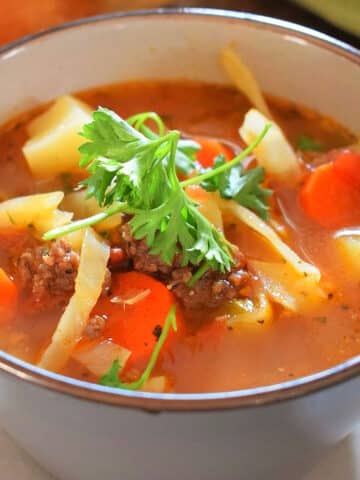 Beef and cabbage soup in blue soup bowl.
