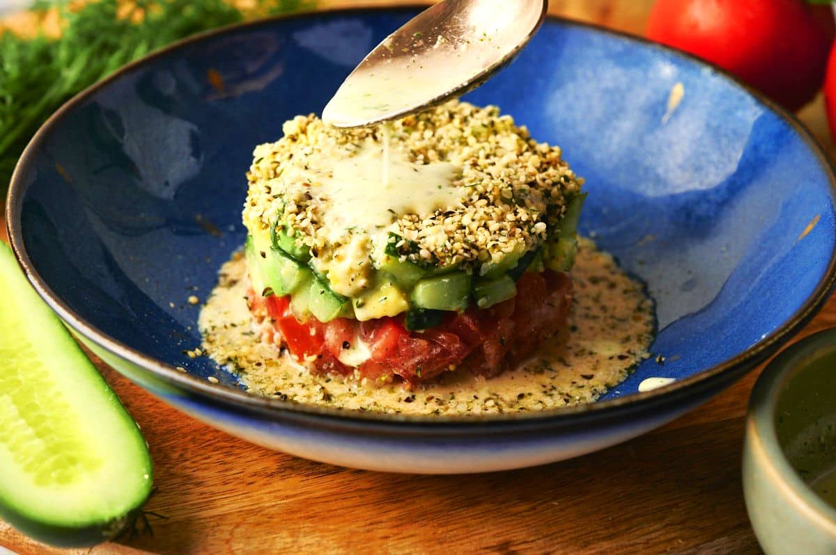 Hemp seed salad with dressing drizzling from a spoon.