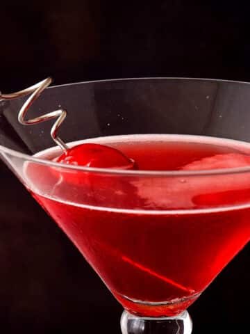 Hibiscus cosmo in martini glass with cherry.