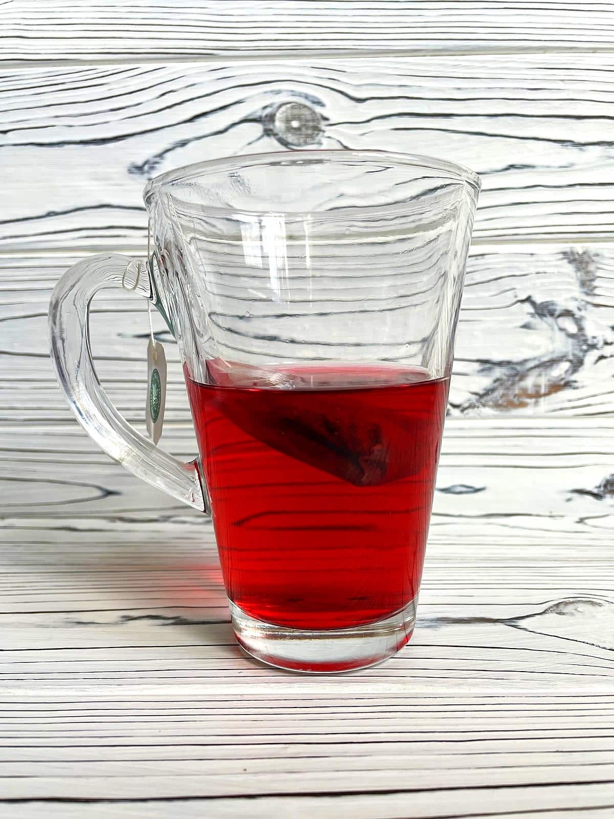 Hibiscus tea steeping in glass mug.