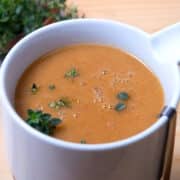 Brown gravy in gravy dish with fresh herbs.