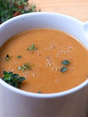 Brown gravy in gravy dish with fresh herbs.