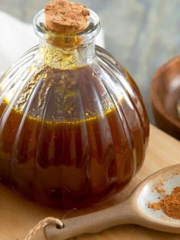 Pumpkin spice syrup in bottle with pumpkin pie spices in a spoon.