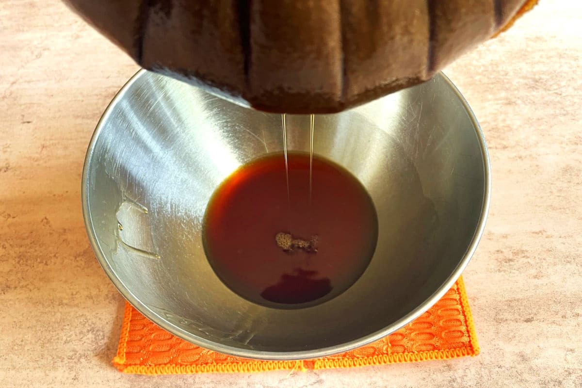 Pumpkin spice syrup straining through nut milk bag into bowl.