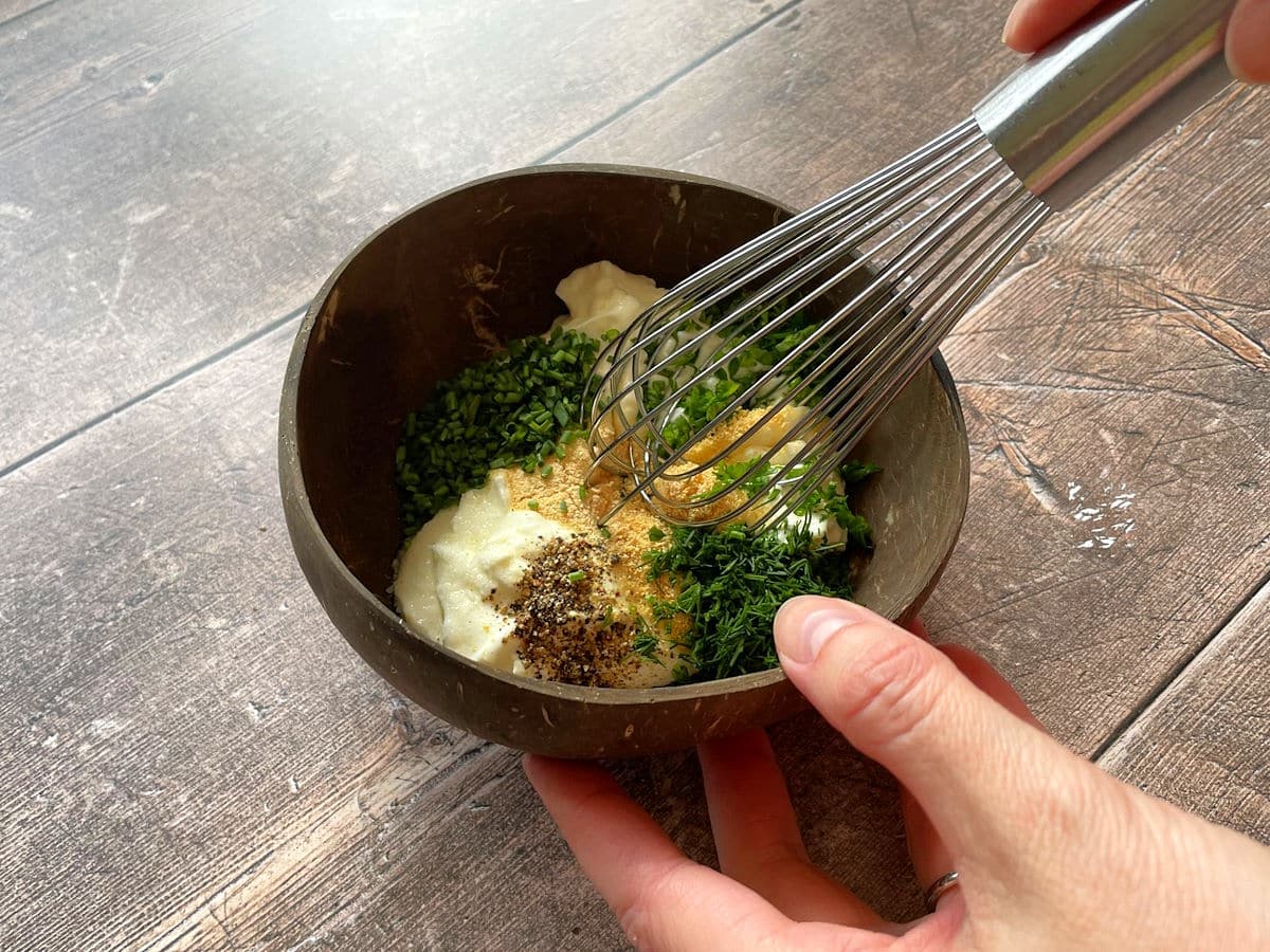 Ranch dressing ingredients in bowl with whisk.