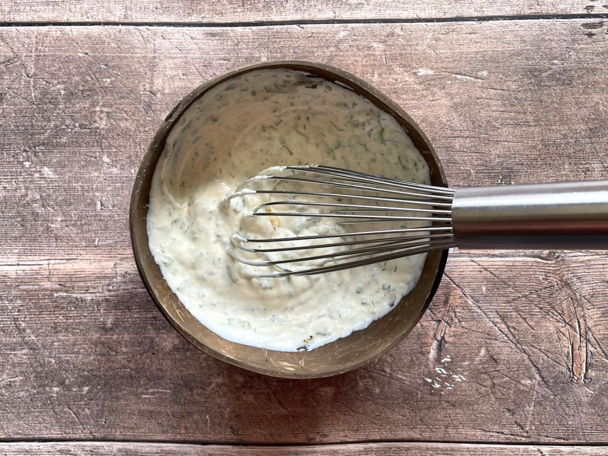 Ranch dressing ingredients combine in bowl with whisk.