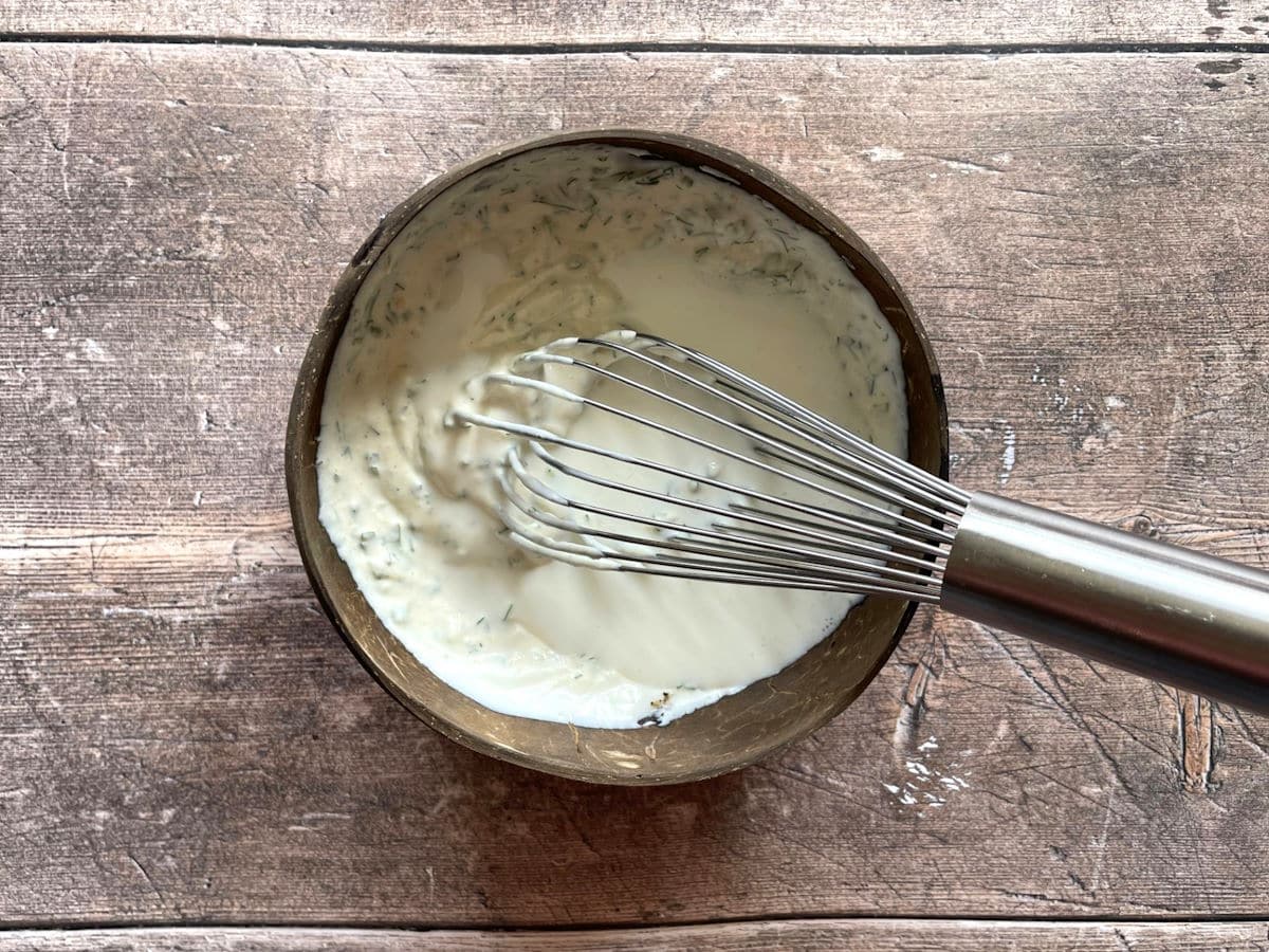 Ranch dressing whisked together with buttermilk in a small bowl.