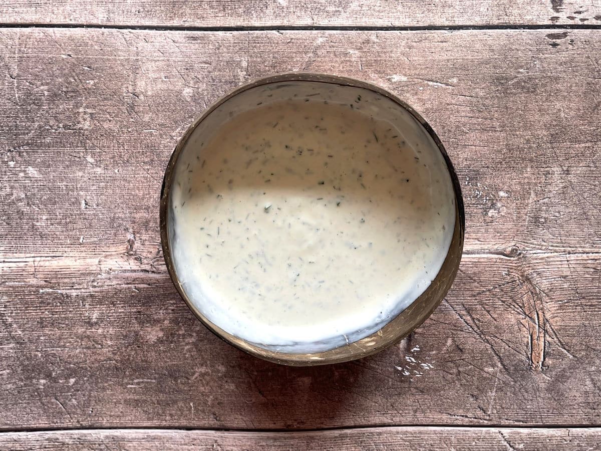 Homemade ranch dressing combined in small, brown bowl.