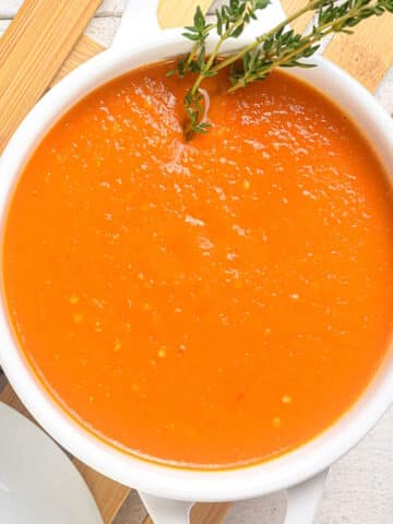 Homemade roasted garlic tomato soup in white soup bowl.