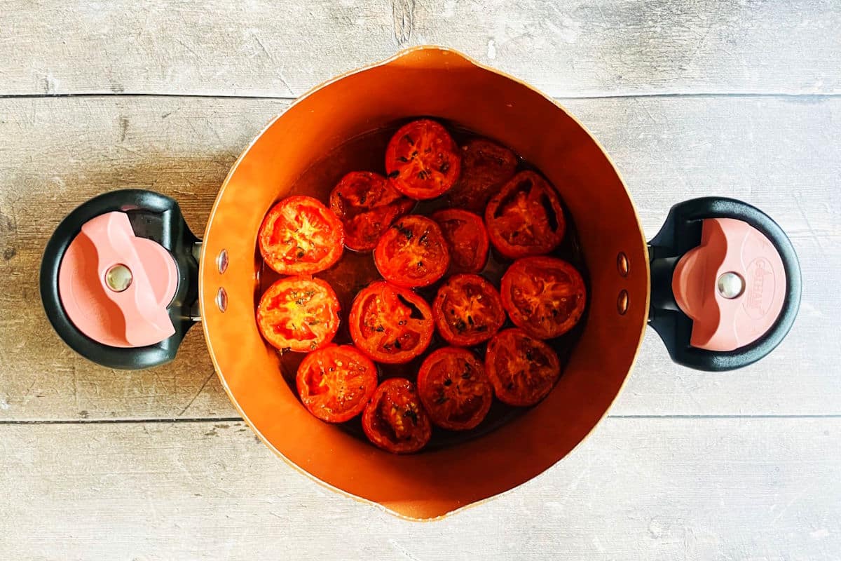Roasted tomatoes and broth in pot.