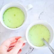 Matcha latte in mugs with spoon.