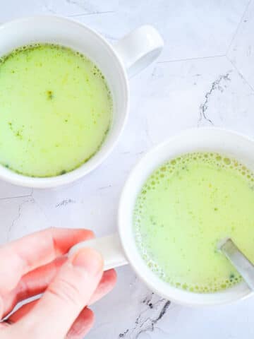 Matcha latte in mugs with spoon.