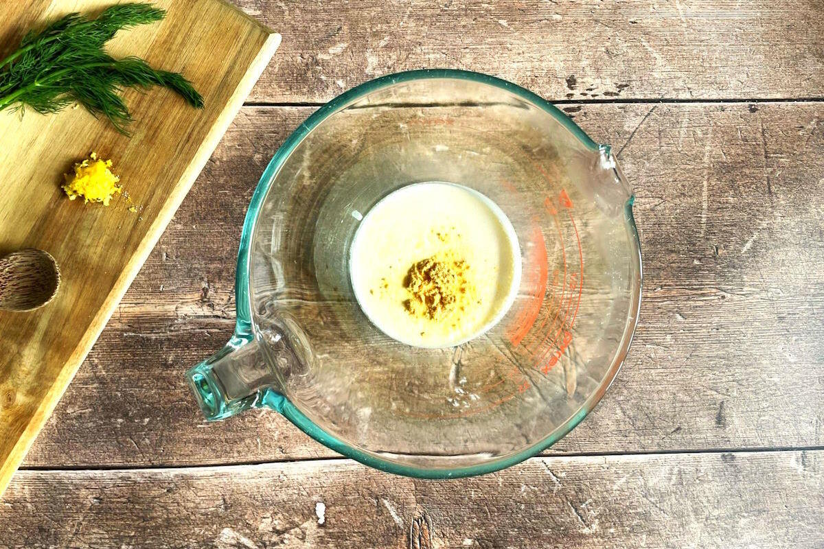 Heavy cream and mustard powder in measuring glass.