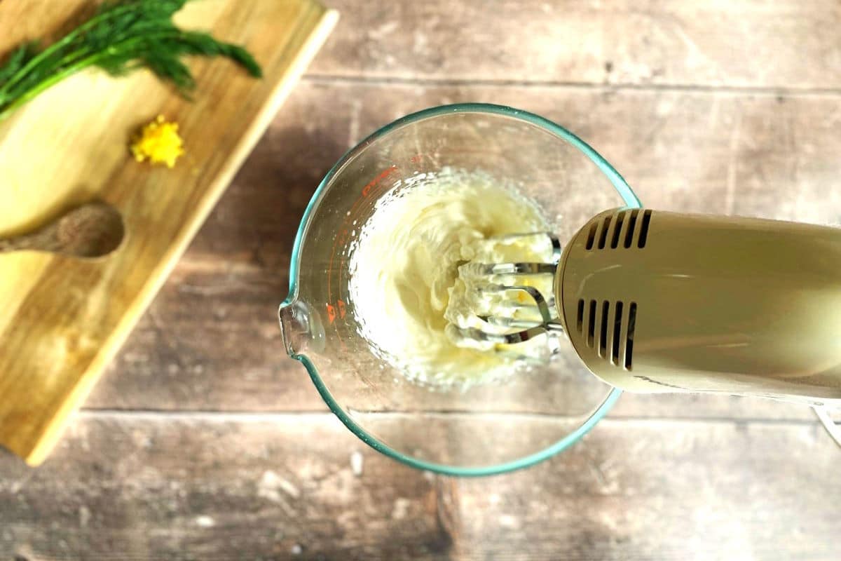 Lemon dill whipped cream getting whipped with hand mixer.