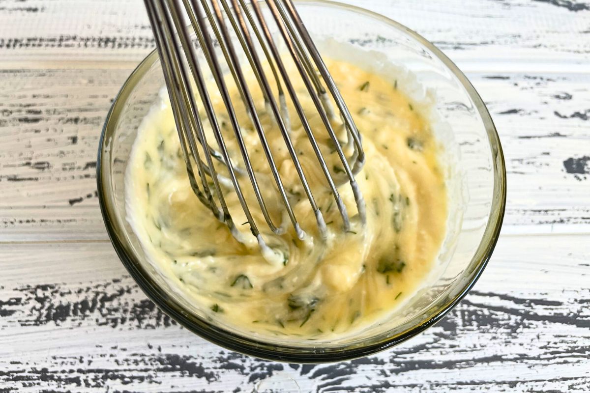 Honey dill sauce in bowl with whisk.