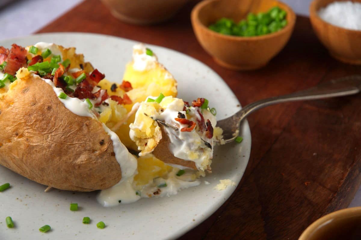 Loaded baked potato on plate with fork.