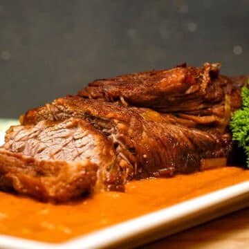 Braised beef with pureed vegetables on white dish.