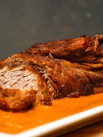 Braised beef with pureed vegetables on white dish.