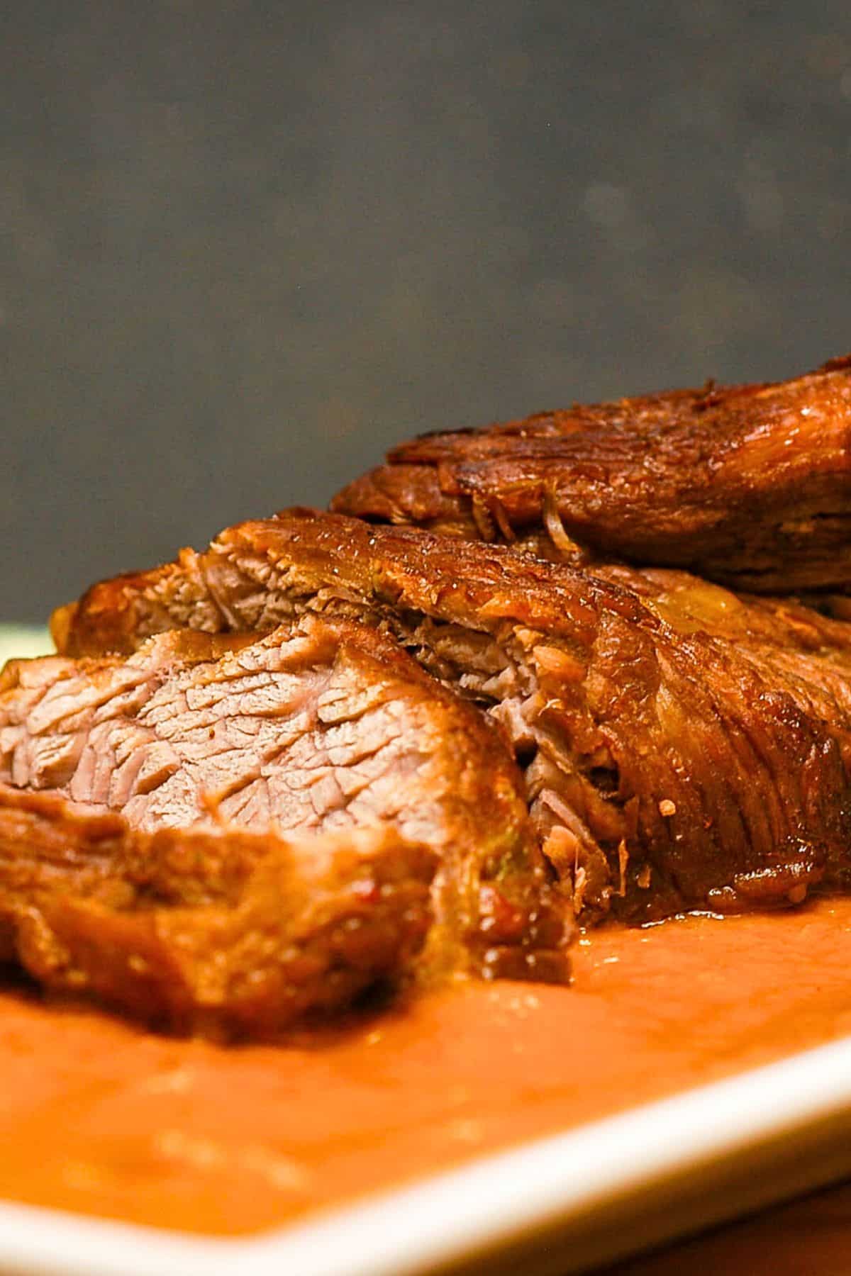 Braised beef with pureed vegetable sauce on white dish.