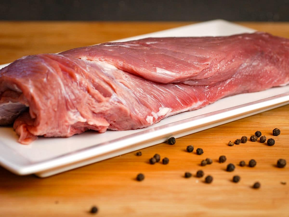 Raw beef roast on white dish.