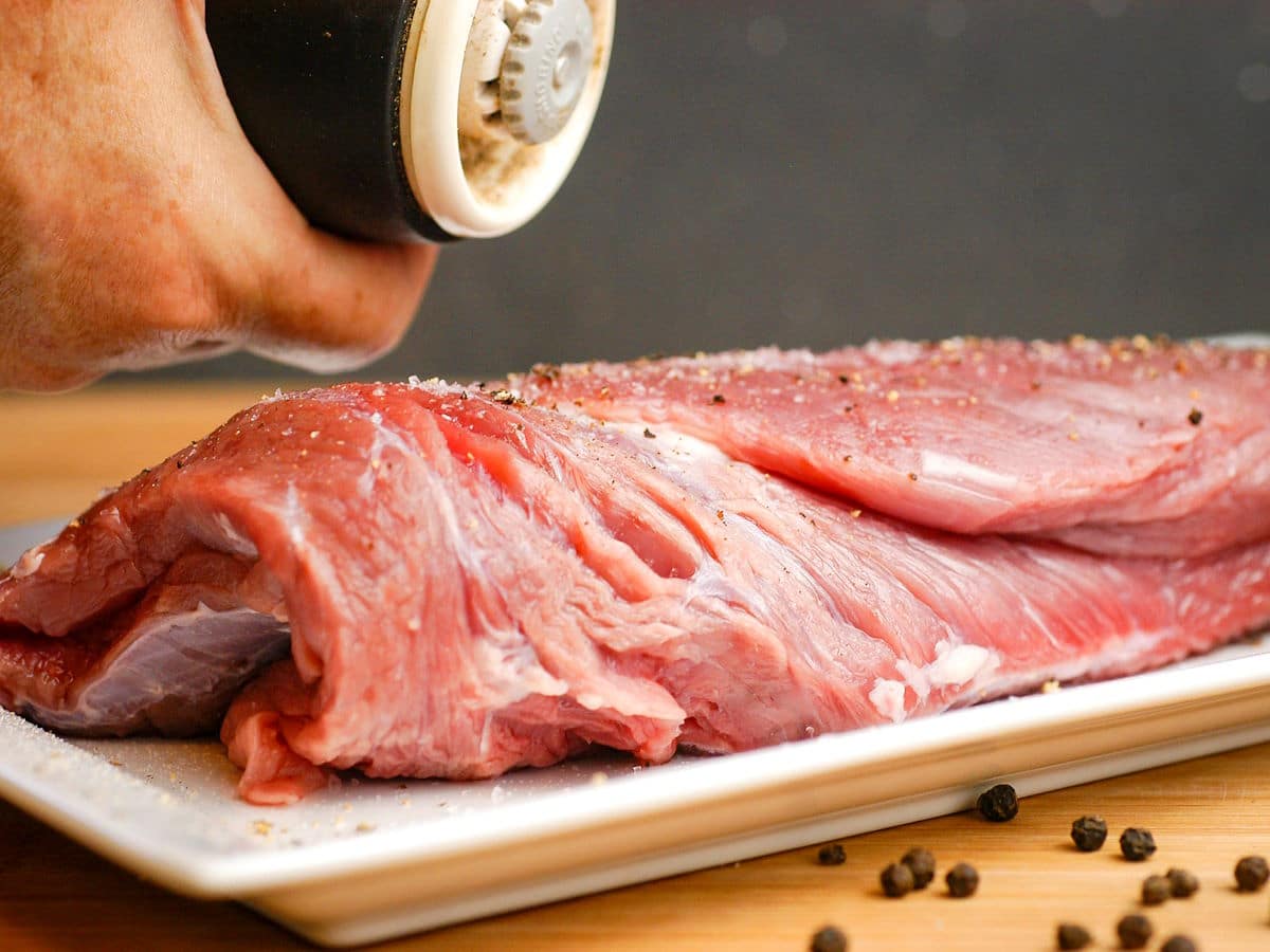 Raw beef roast seasoned with salt and pepper.