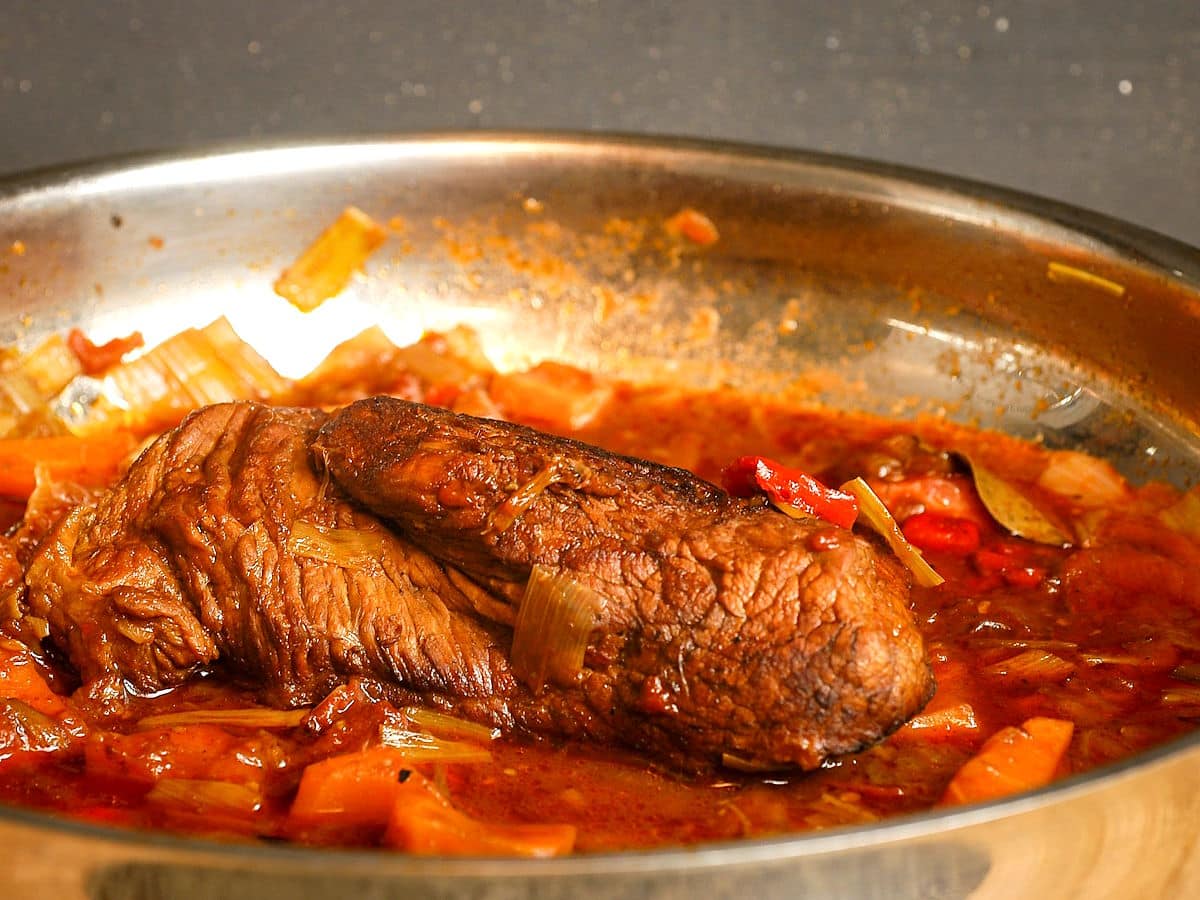 Braised beef in pan with vegetables.