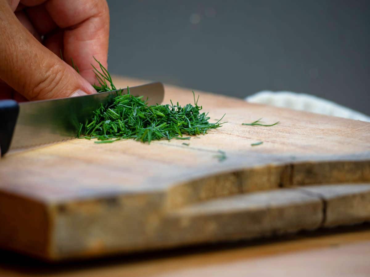 Fresh dill getting chopped with knife.