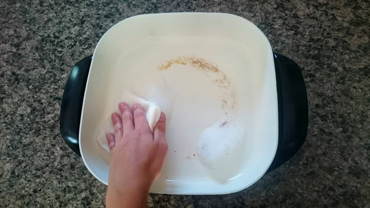 washing electric skillet with damp towel Electric skillet getting cleaned with paper towel and soapy water.