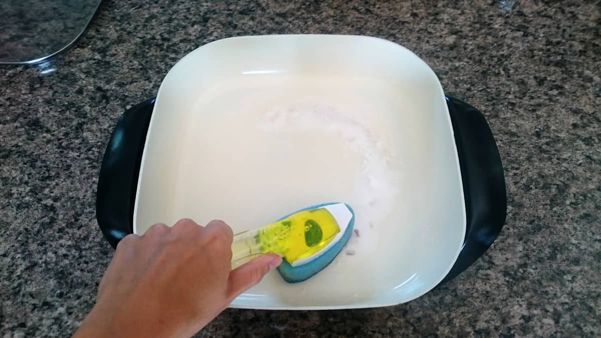scrubbing electric skillet A hand with brush scrubbing electric skillet with baking soda paste.