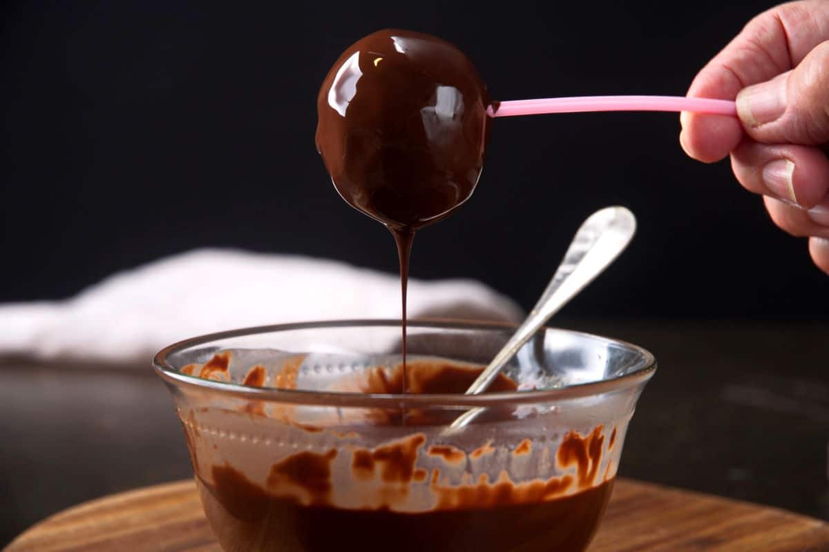 Cake pop over bowl with chocolate coating dripping.