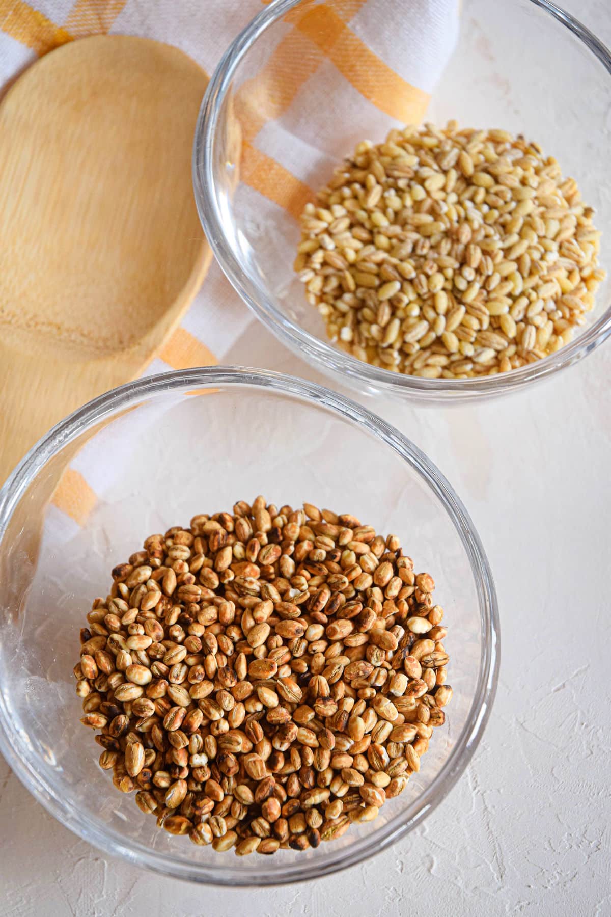 Uncooked pearl and hulled barley in bowls.