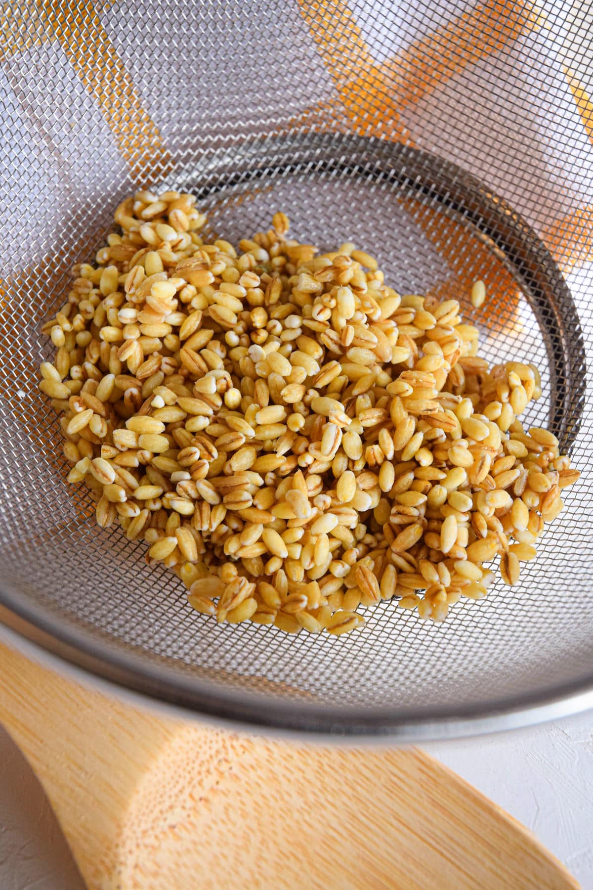 Uncooked barley in mesh strainer.