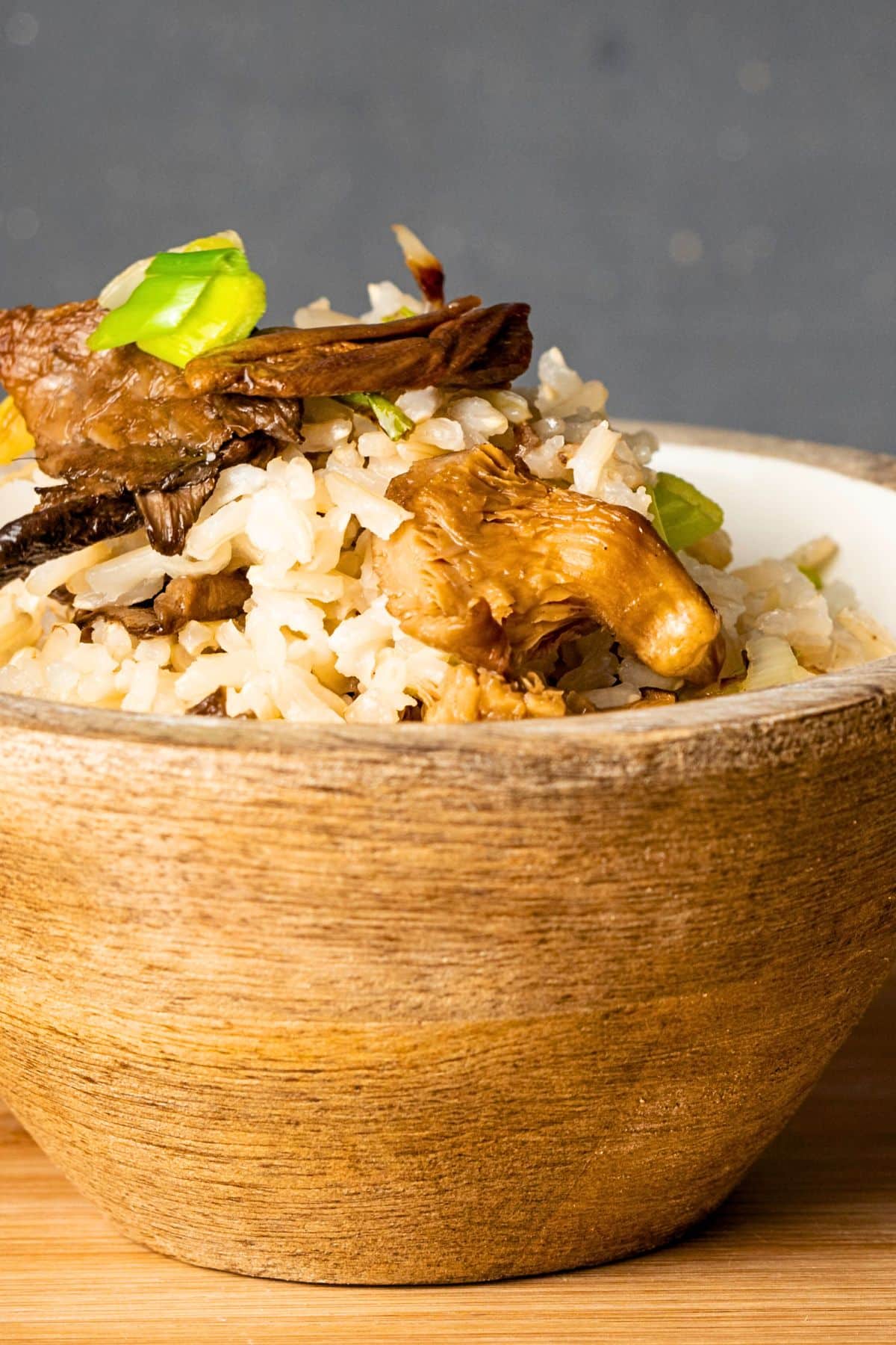 Brown rice in brown bowl with mushrooms.