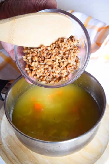 Hulled barley in bowl over pot of soup.