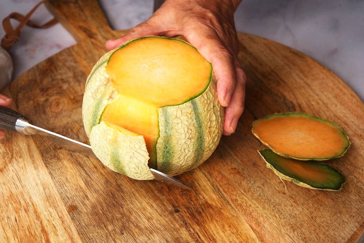 Cantaloupe getting peeled with knife.
