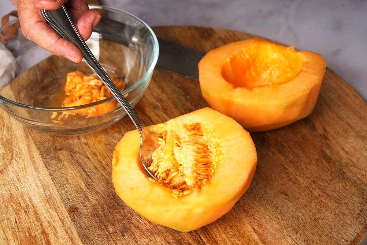 Seeds getting scooped out of cantaloupe.